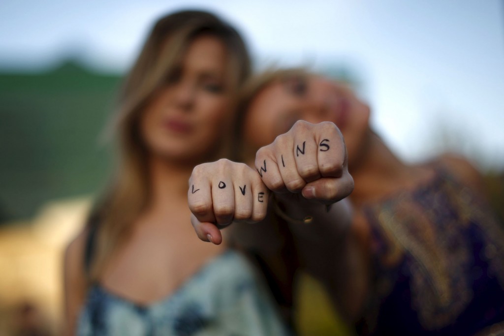 Cherilyn Wilson, 26, (L) and Chelsea Kane, 26, display their fists, with the message "Love Wins" written on them, as they pose at a celebration rally in West Hollywood, California, United States, June 26, 2015. The U.S. Supreme Court ruled on Friday that the U.S. Constitution provides same-sex couples the right to marry in a historic triumph for the American gay rights movement. REUTERS/Lucy Nicholson - RTX1I0I9